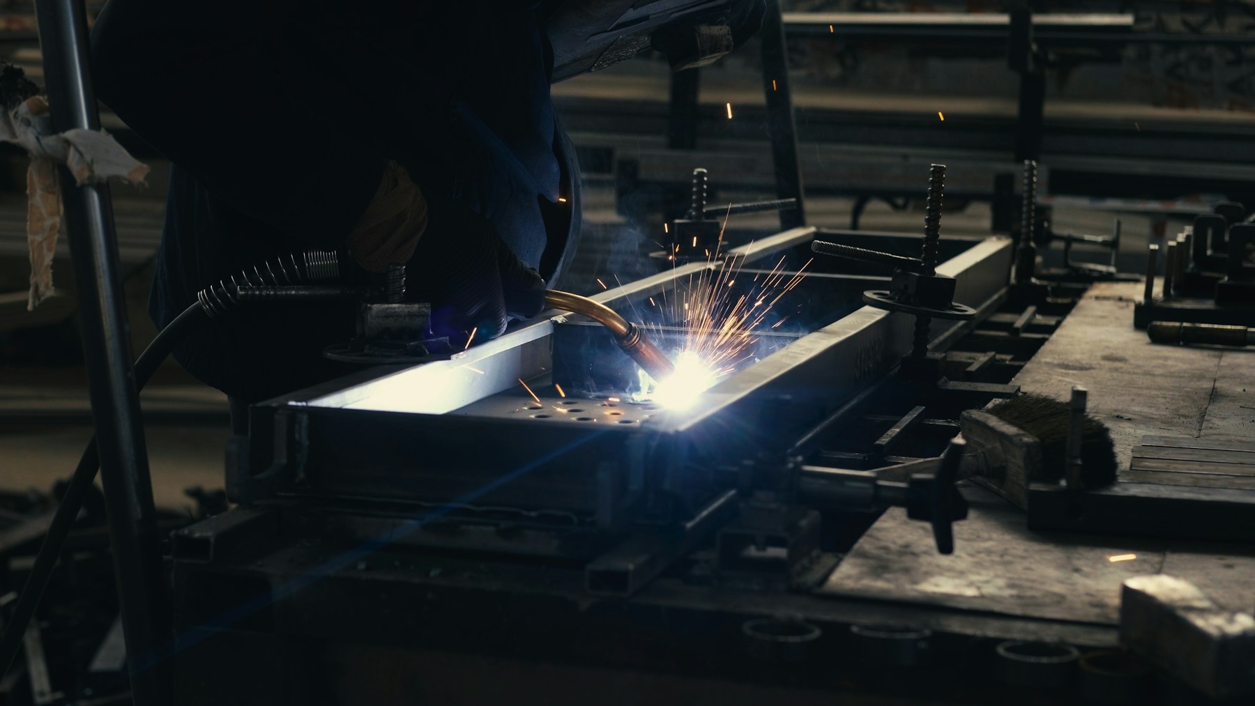 Welder fabricating steel at a workbench
